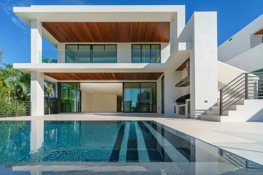 Modern white coastal residence with pool at dusk